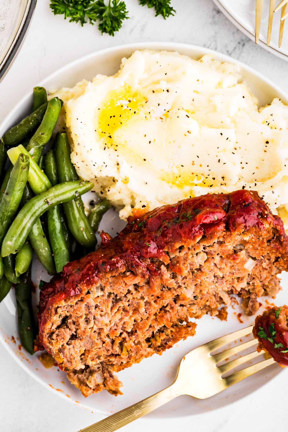 overhead view of meatloaf slice on plate with mashed potatoes and green beans