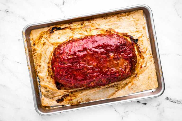 overhead view of fully baked meatloaf on parchment lined baking sheet