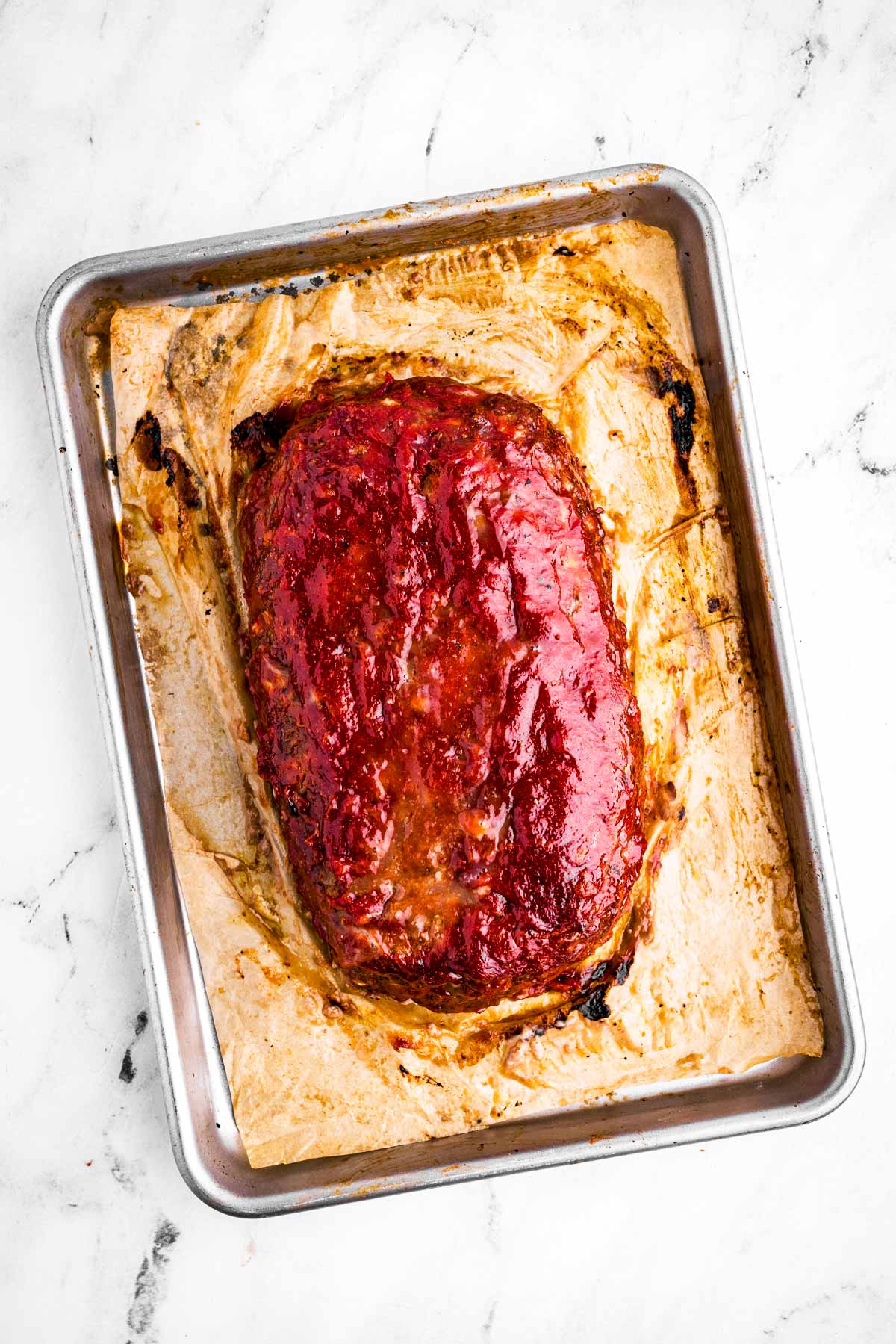 overhead view of fully baked meatloaf on parchment lined baking sheet