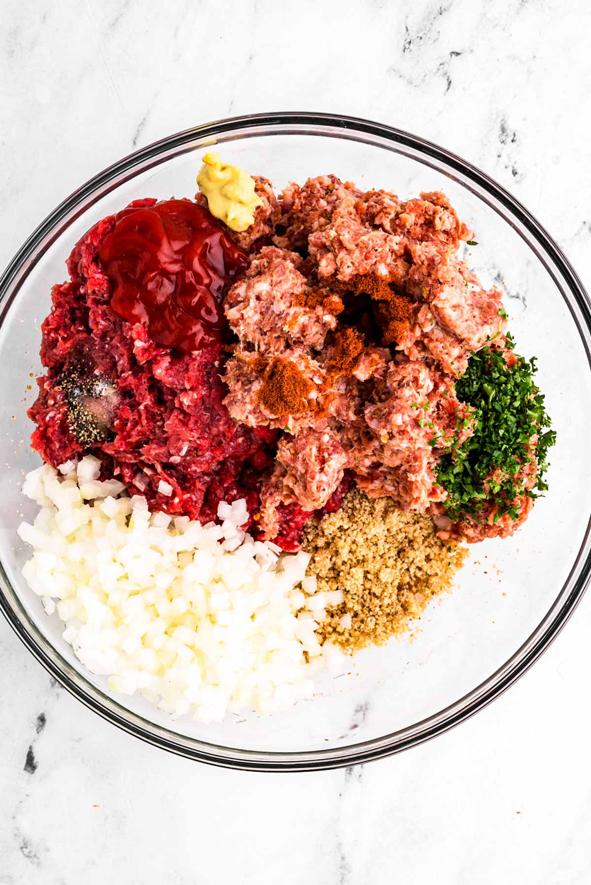 overhead view of ingredients to make meatloaf in glass bowl