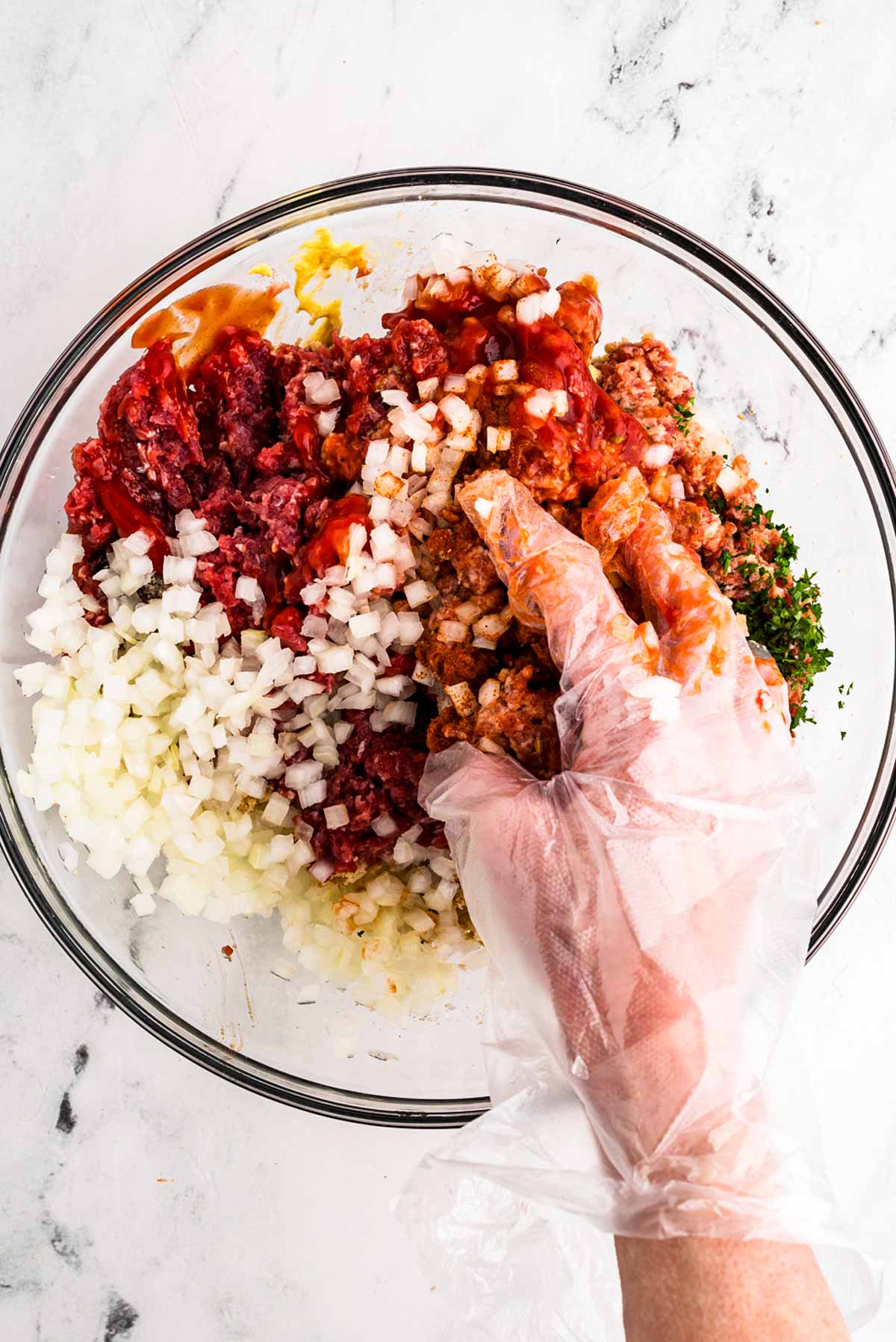 overhead view of gloved hand mixing meatloaf mixture