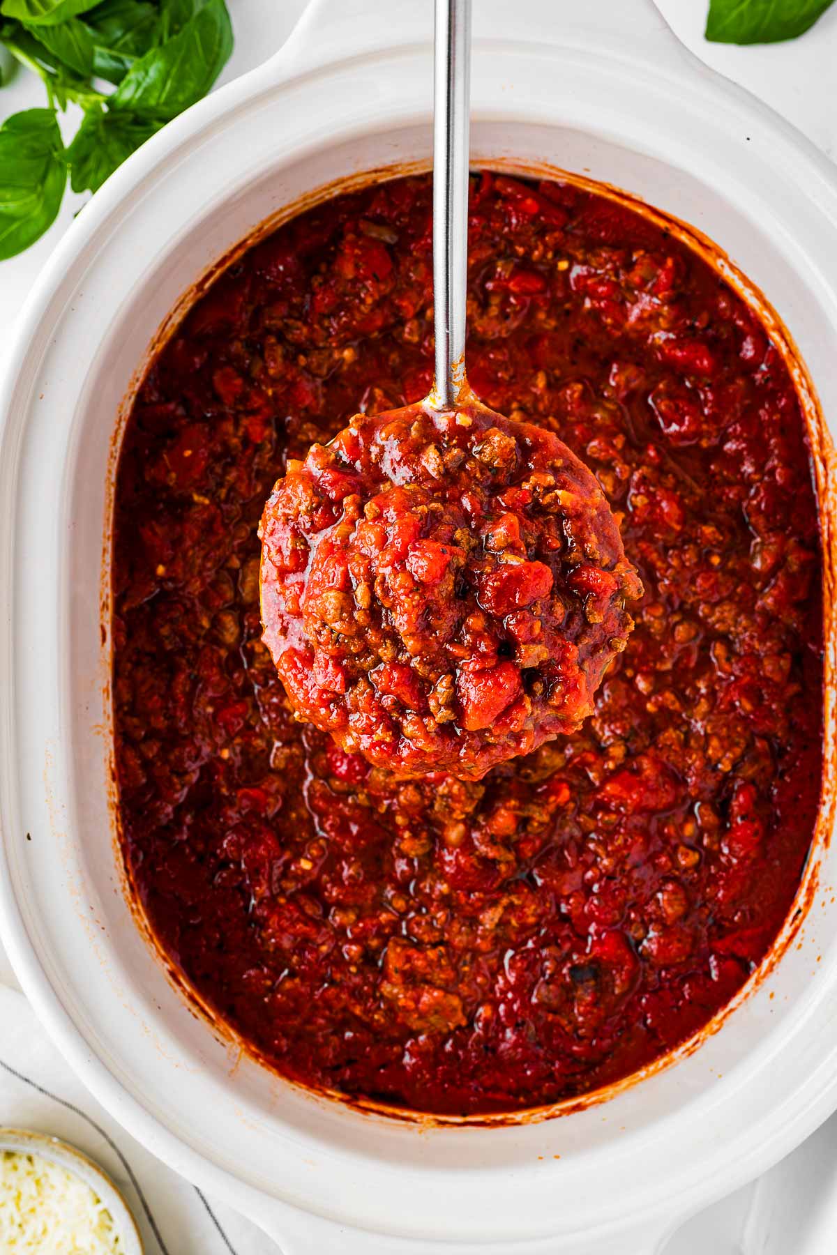 overhead view of spaghettis sauce on ladle over slow cooker