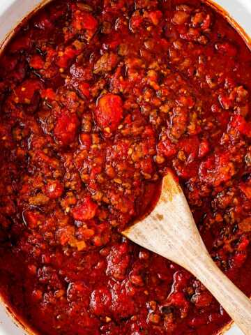 overhead view of spaghetti sauce in crock pot with wooden spoon