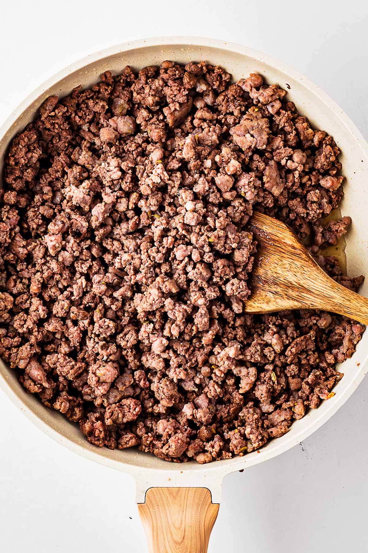 overhead view of browned ground beef and sausage in skillet