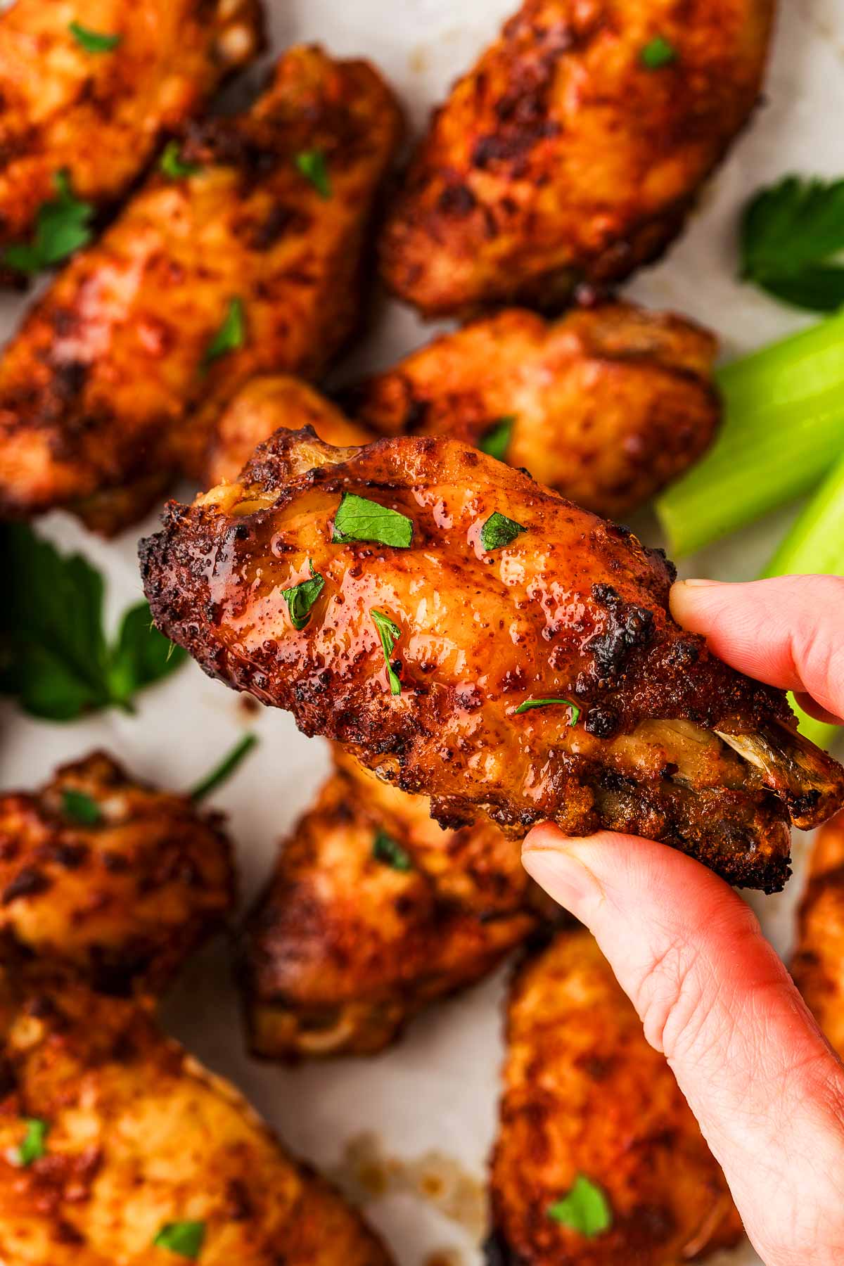 overhead view of female hand holding baked chicken wing