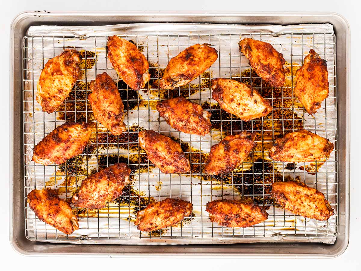 overhead view of fully baked chicken wings on wire rack, golden and crispy