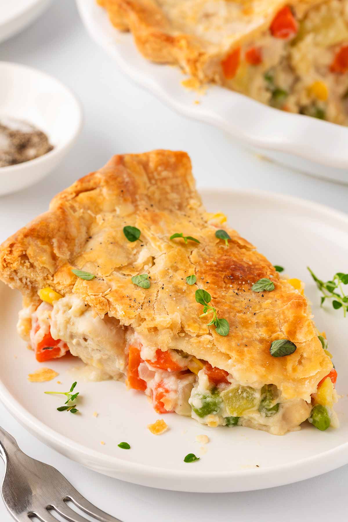 frontal shot of a slice of chicken pot pie on a plate, showing the creamy filling inside