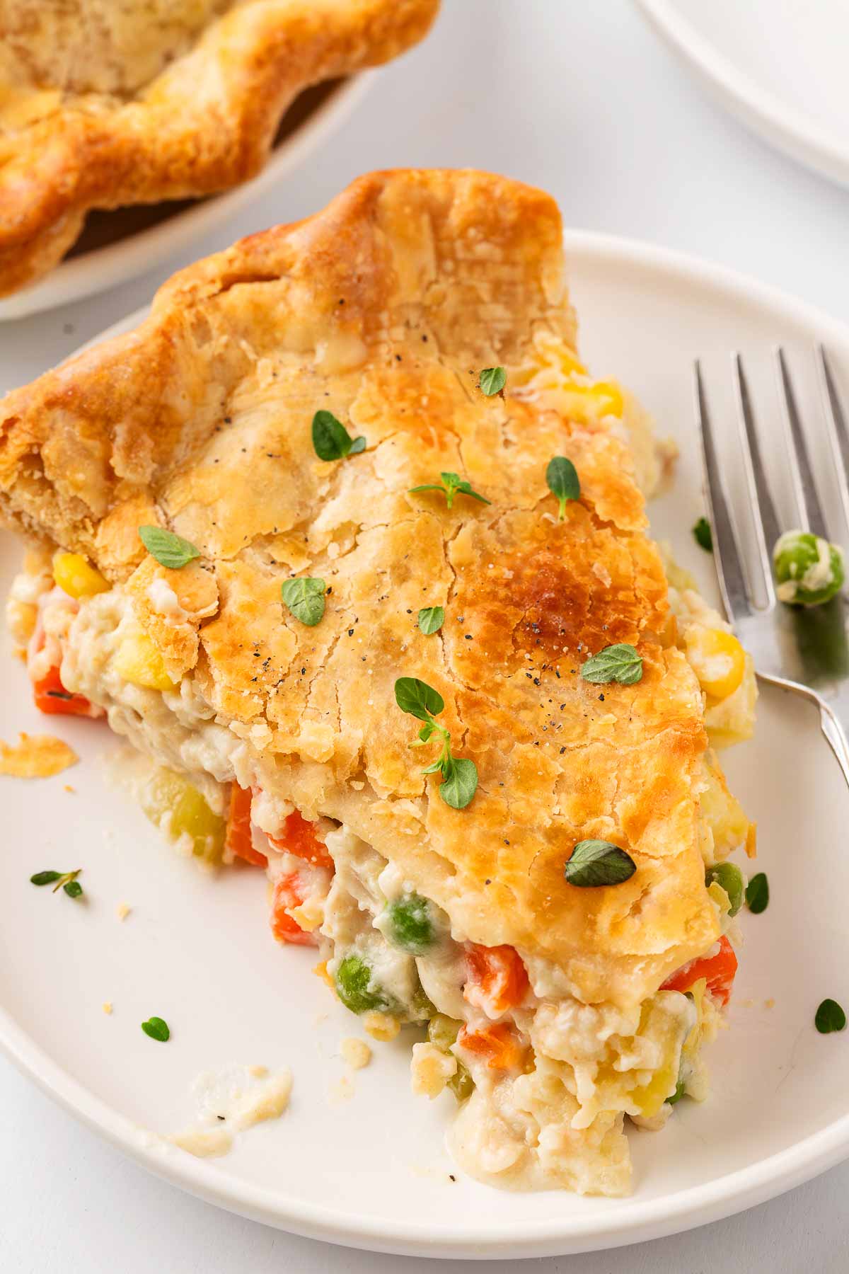 frontal angled shot of a slice of chicken pot pie on a plate, showing the creamy filling inside