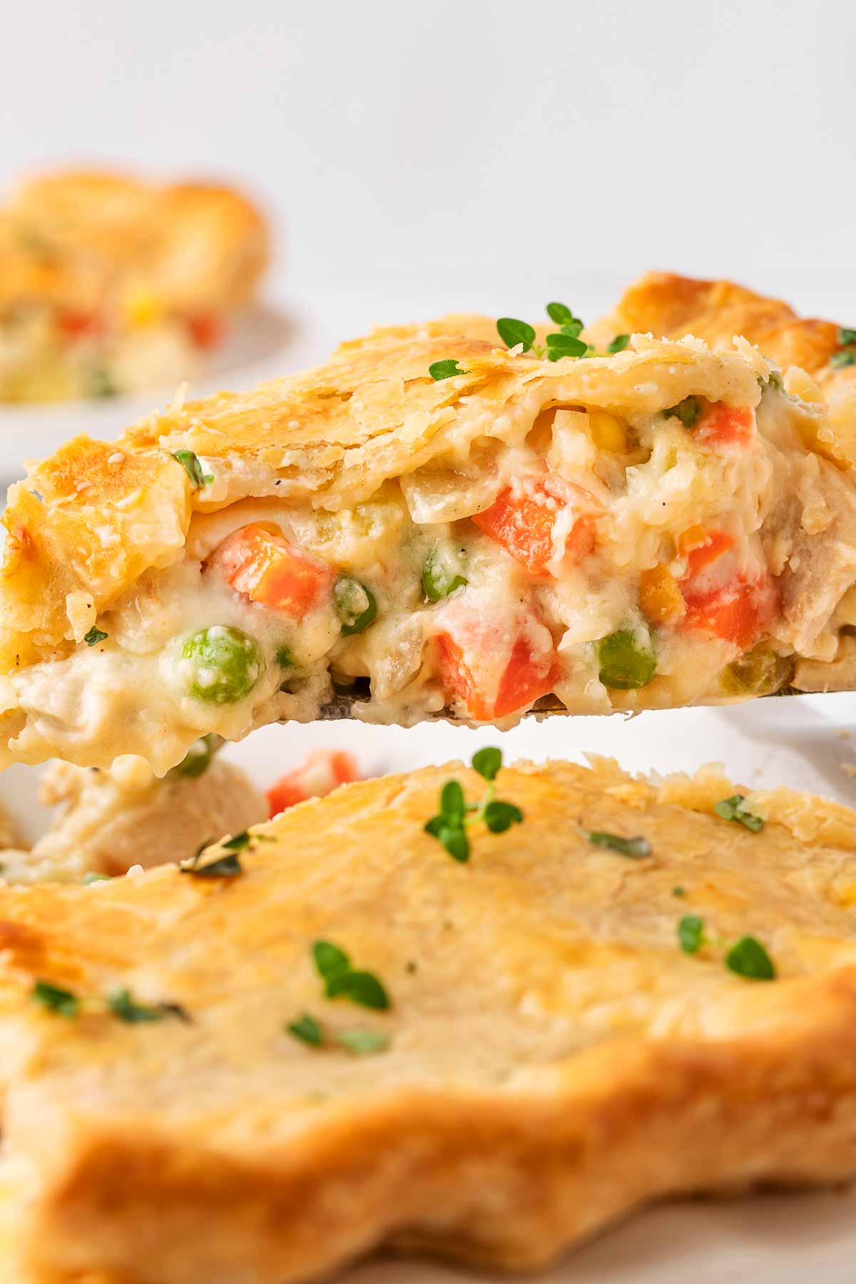 close-up of a slice of chicken pot pie being lifted with a cake server, showing the rich filling