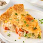 frontal shot of a slice of chicken pot pie on a plate, showing the creamy filling inside