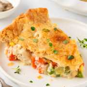 frontal shot of a slice of chicken pot pie on a plate, showing the creamy filling inside