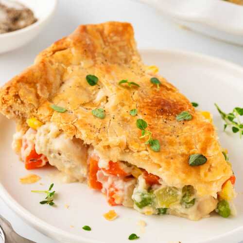 frontal shot of a slice of chicken pot pie on a plate, showing the creamy filling inside