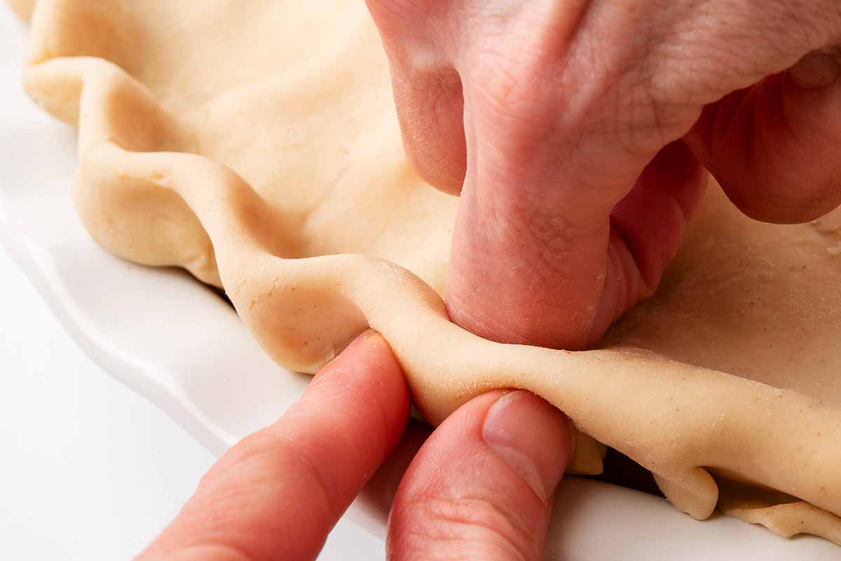 close-up of female hands crimping pie crust