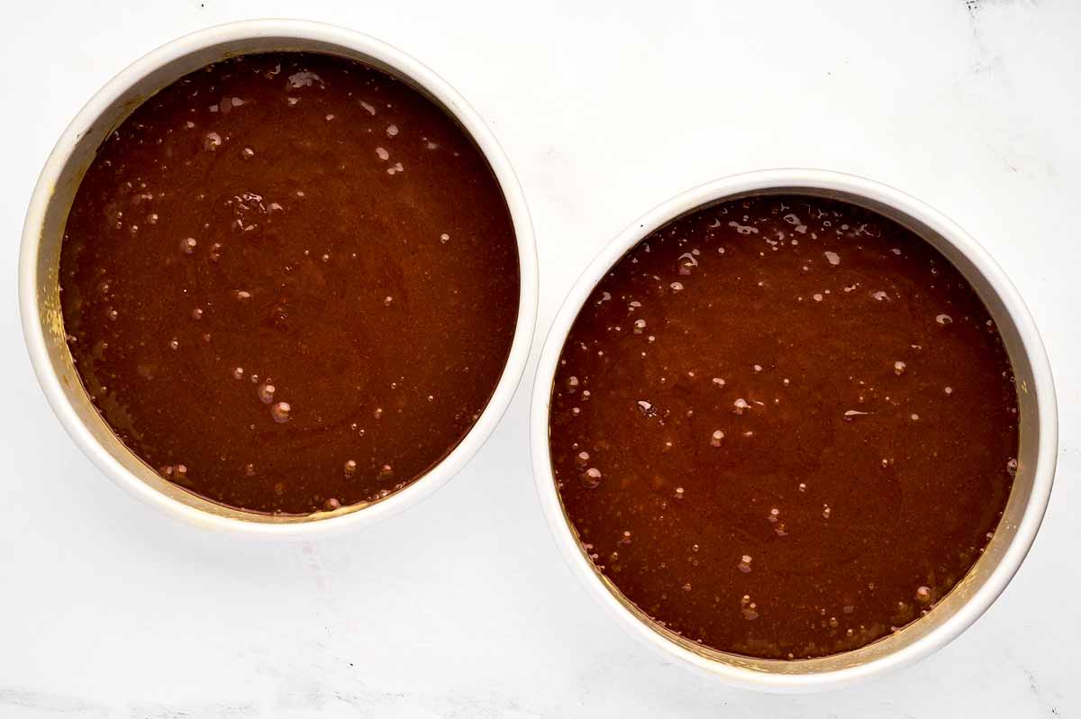 overhead view of two cake pans filled with chocolate cake batter