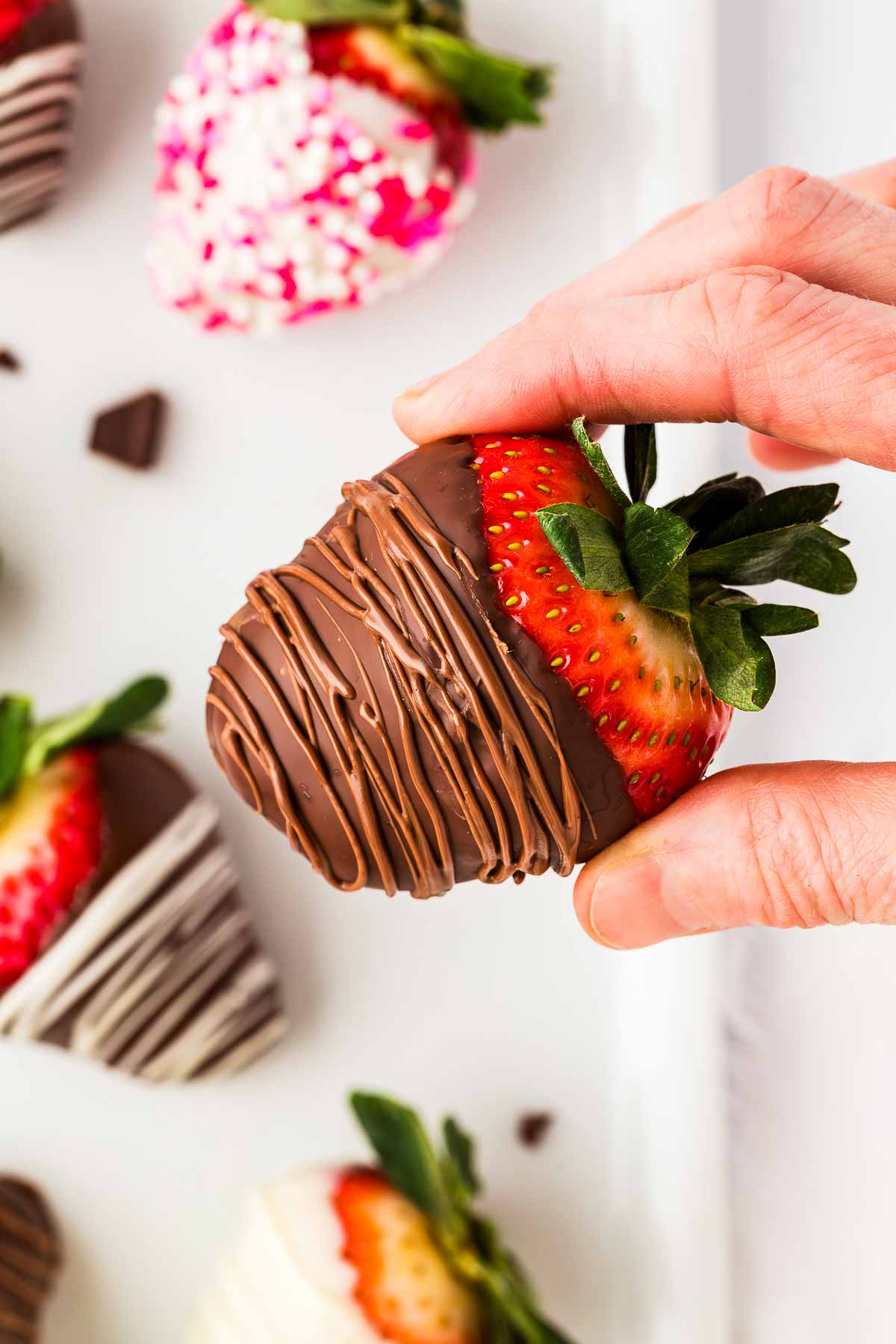 overhead view of female hand holding a chocolate covered strawberry