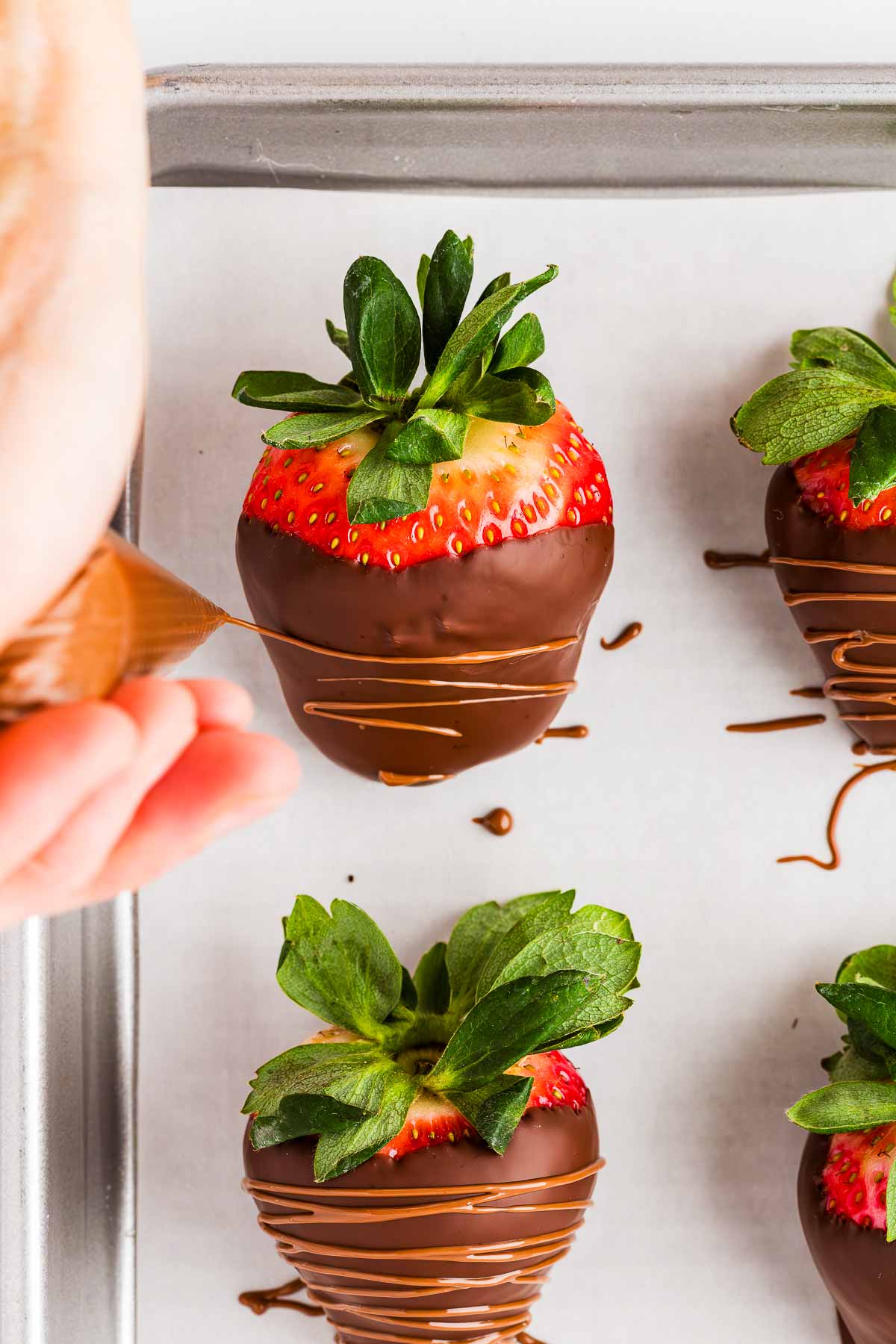 overhead view of milk chocolate drizzling over chocolate covered strawberry