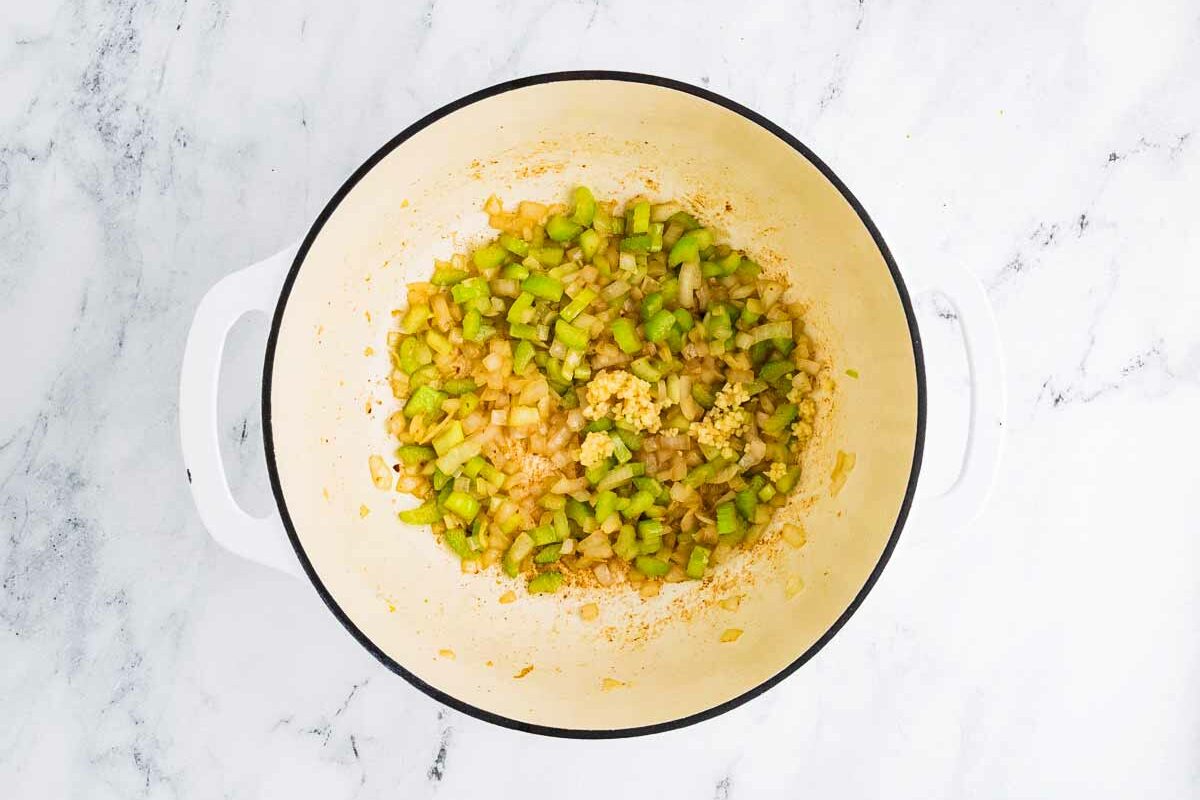 overhead view of diced onions and celery cooking in a Dutch oven