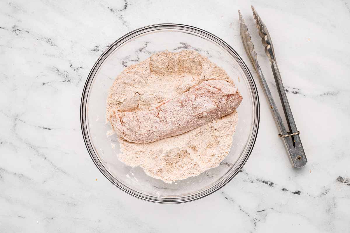 overhead view of raw chicken breast in seasoned flour