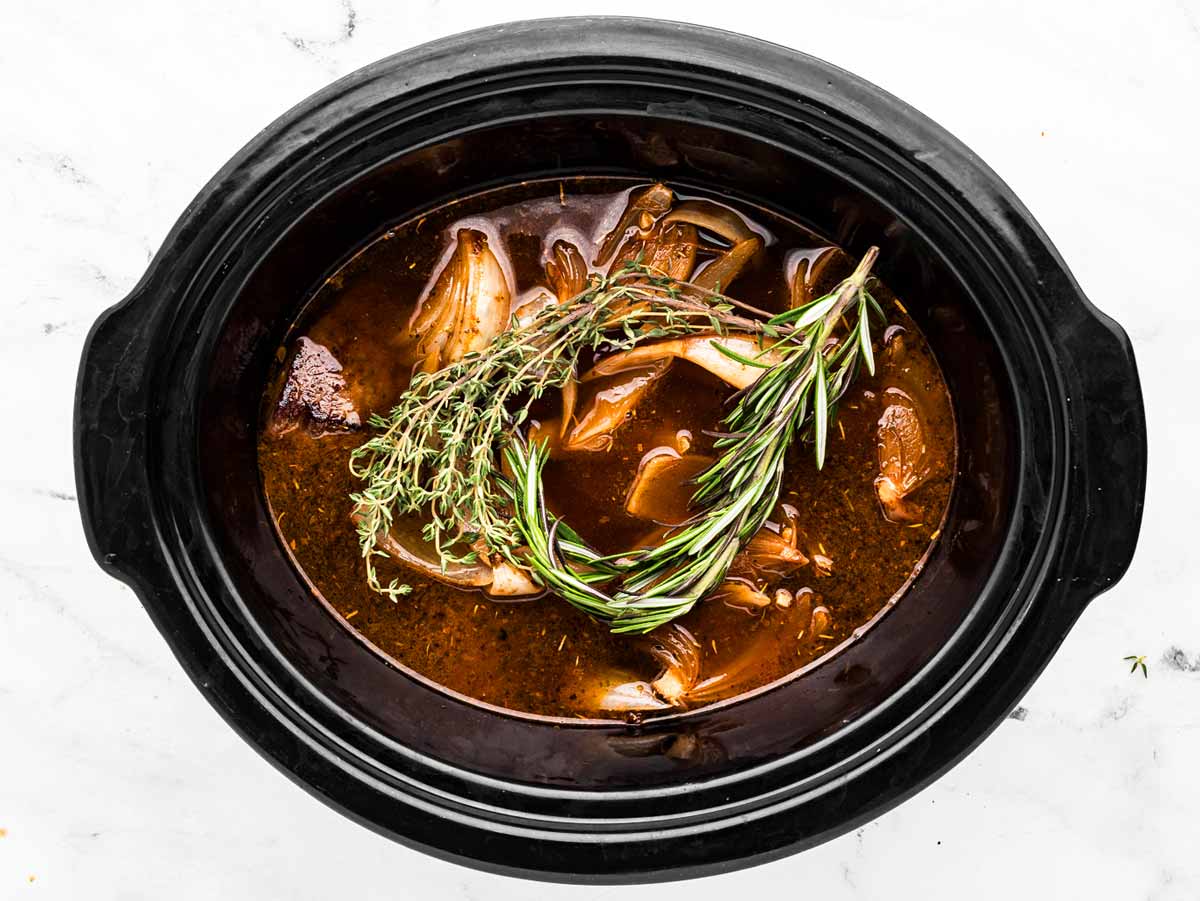 overhead view of fresh rosemary and thyme sprigs in crockpot