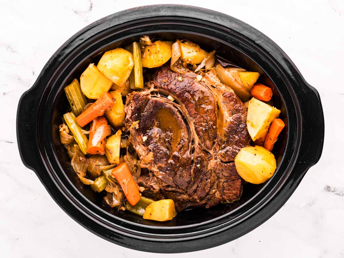 overhead view of fully cooked pot roast with vegetables in crockpot