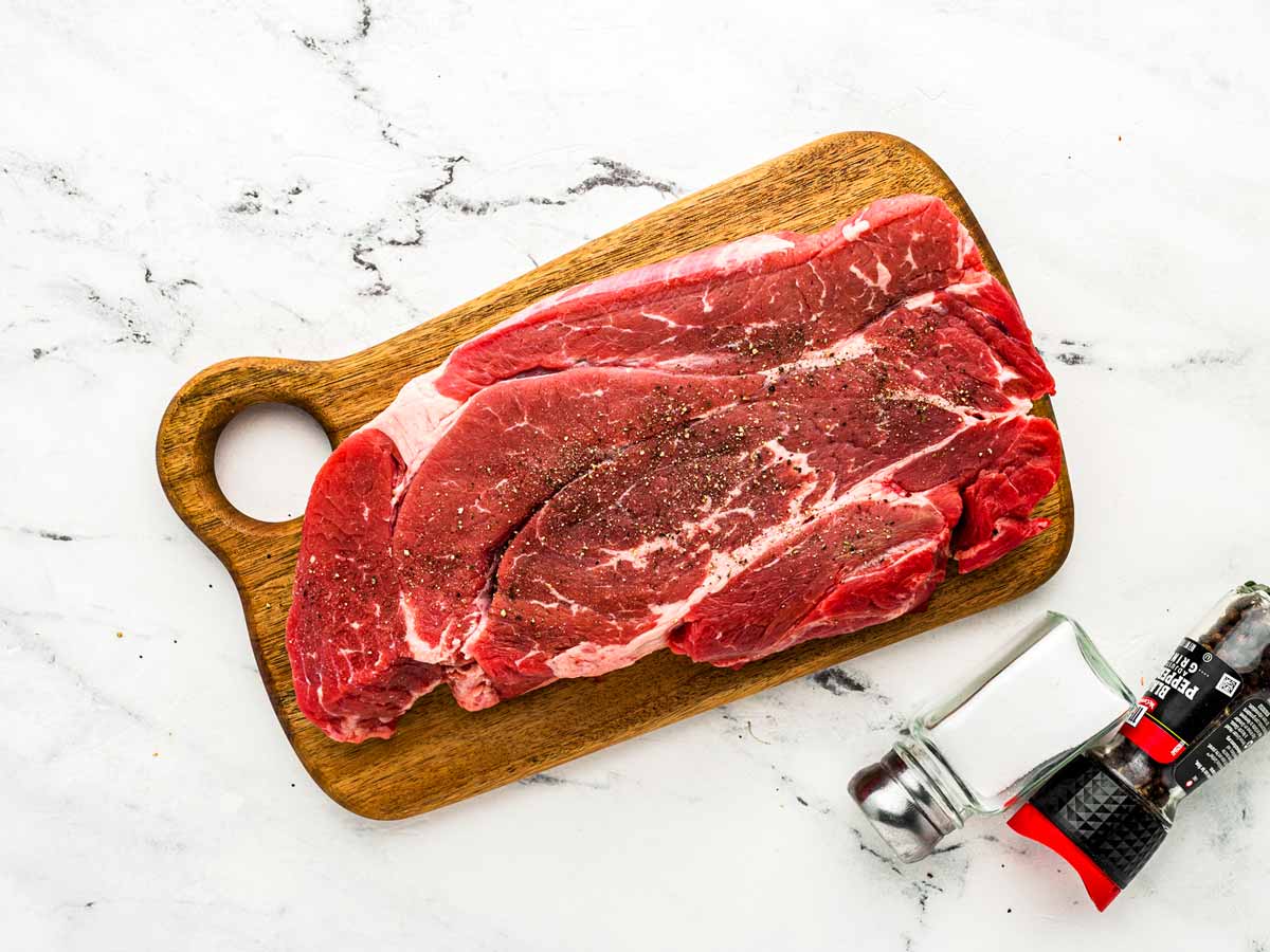 overhead view of chuck roast on cutting board with salt and pepper