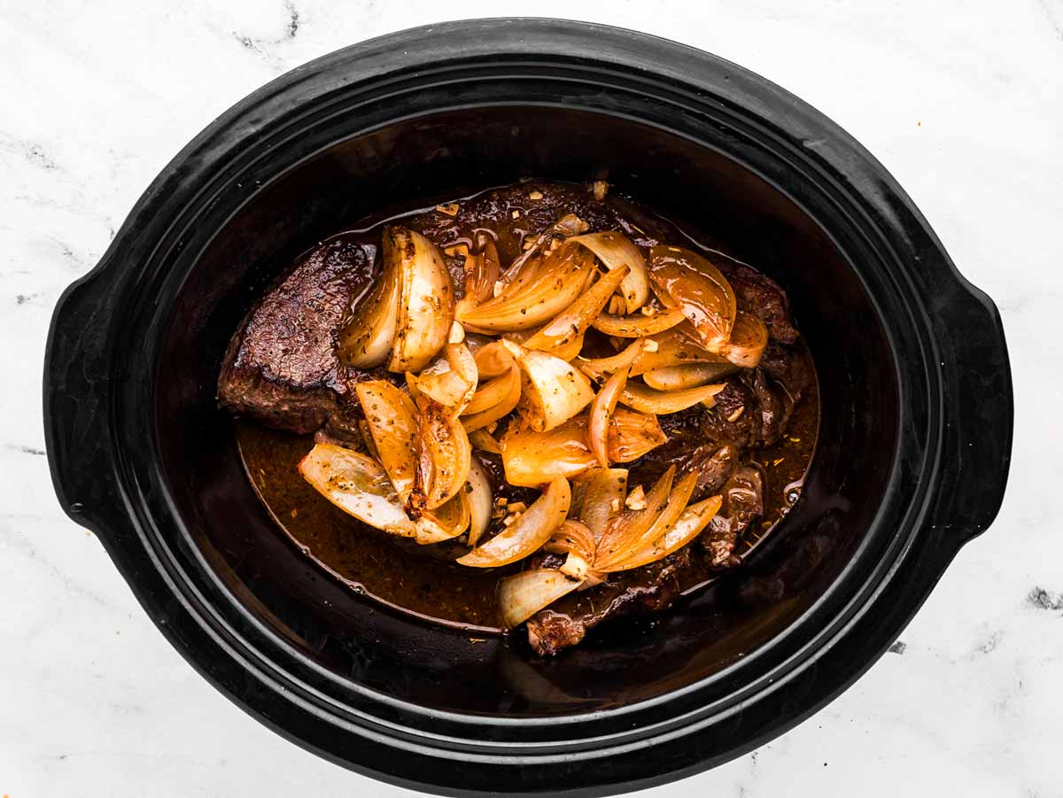 overhead view of crockpot with chuck roast and broth before cooking