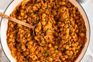 overhead view of hamburger helper in white skillet with wooden spoon stuck in