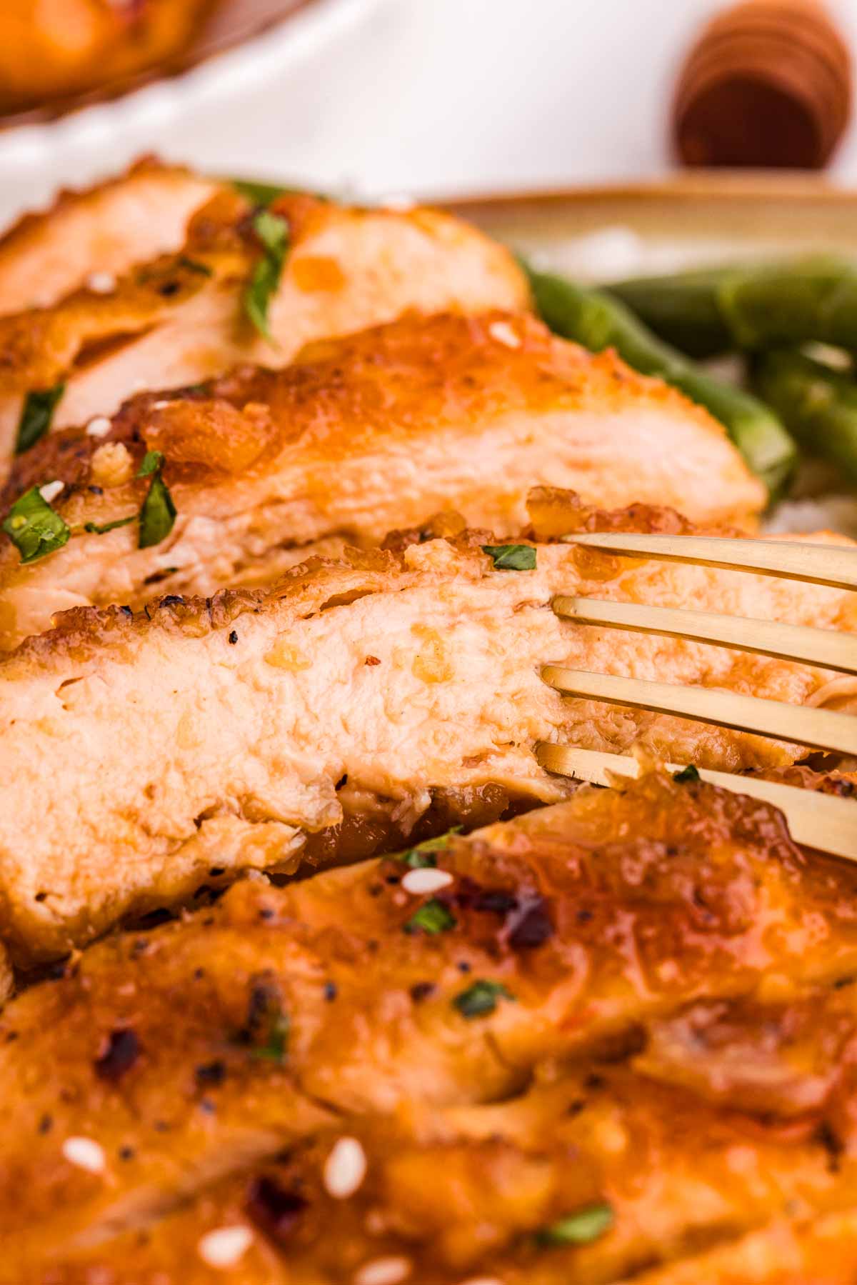 frontal close up view of sliced honey garlic chicken with fork