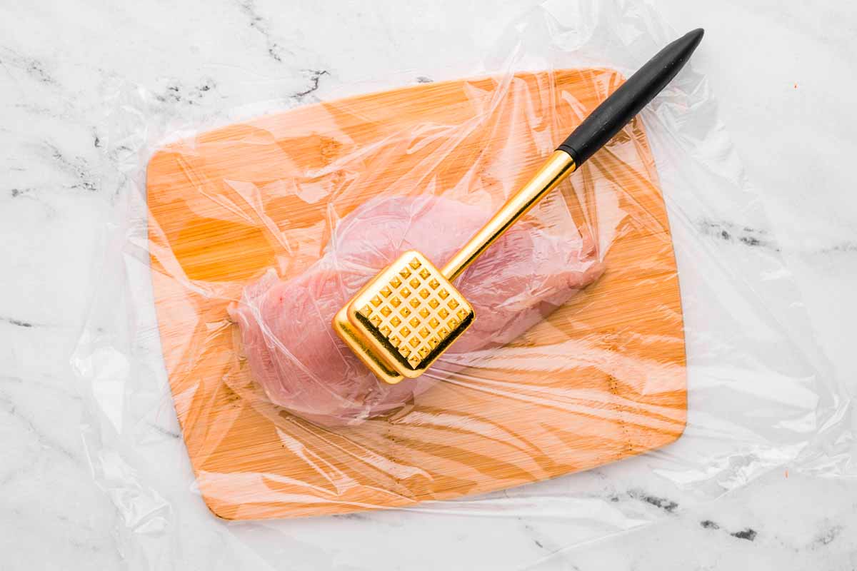 overhead view of chicken being pounded with meat mallet