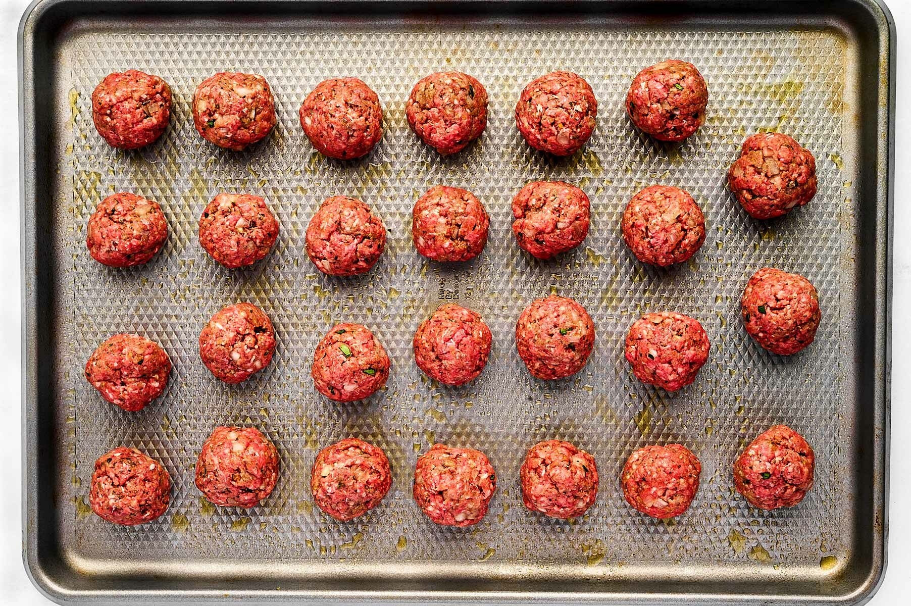 overhead view of unbaked meatballs on baking sheet