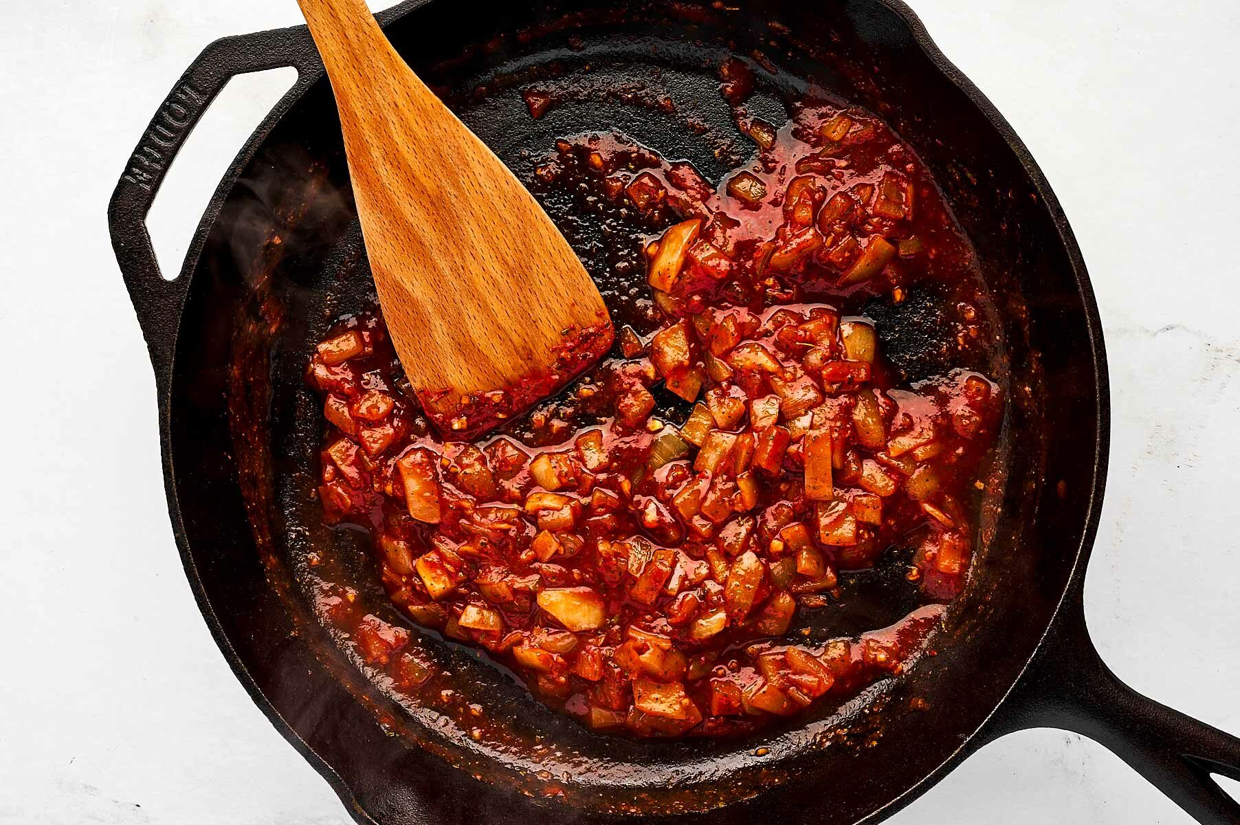 overhead view of aromatics in skillet with red wine