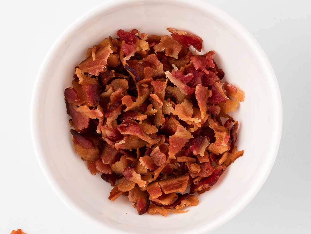 overhead view of cooked and crumbled bacon in white bowl