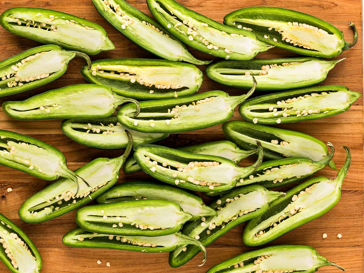 overhead view of fresh jalapeños halved on a cutting board