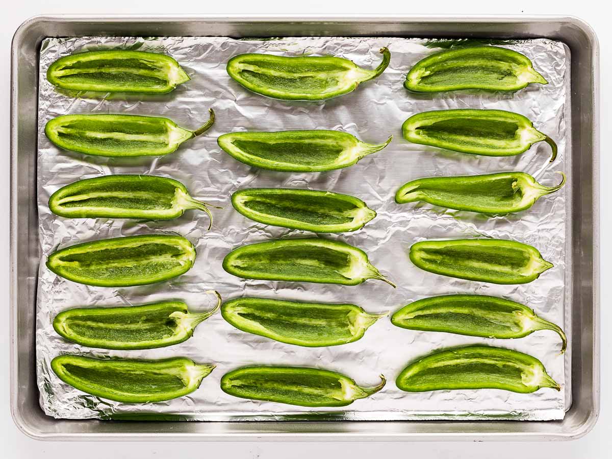 overhead view of jalapeño halves lined up on a baking sheet