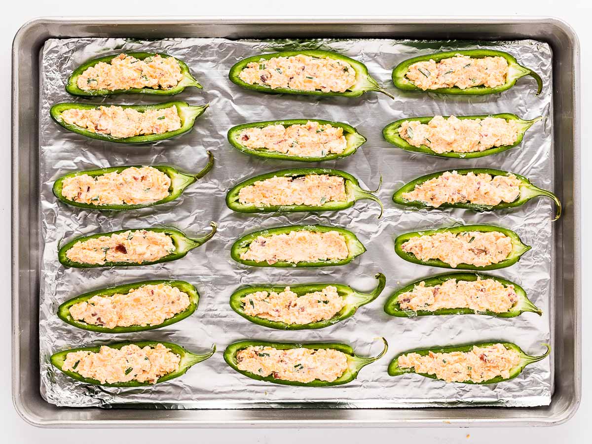 overhead view of filled jalapeños on lined baking sheet