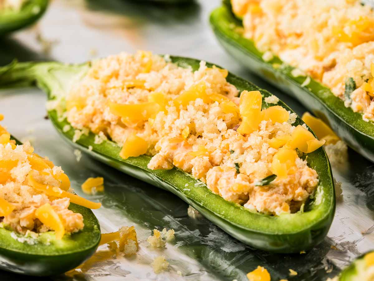 close-up of unbaked jalapeño popper with crispy topping and melted cheese