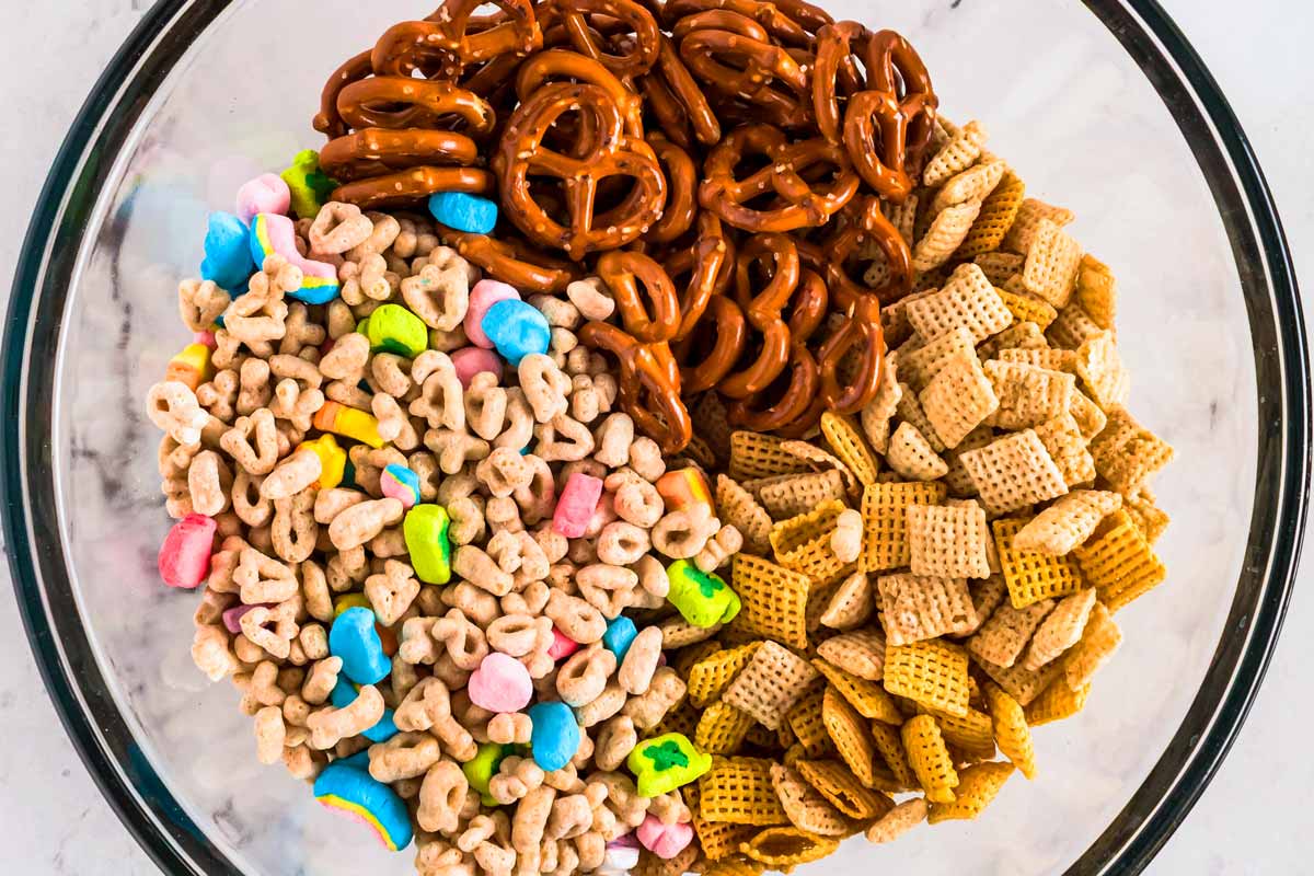 overhead view of ingredients for leprechaun bait Chex mix in glass bowl