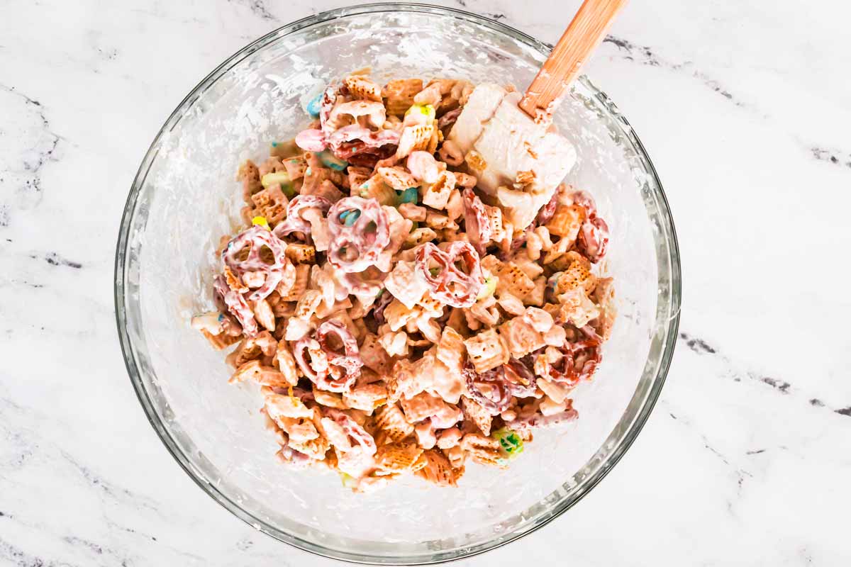 overhead view of leprechaun bait Chex mix with rubber spatula in glass bowl