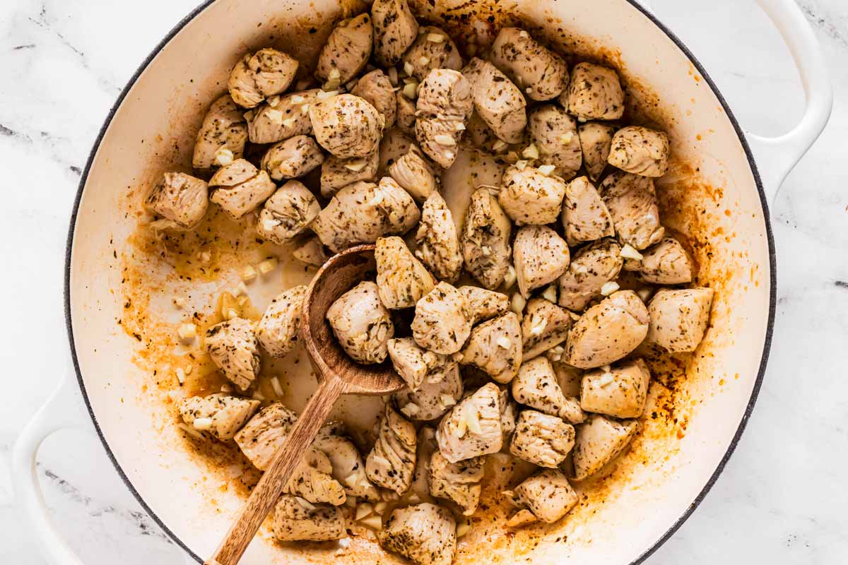 overhead view of cooked seasoned diced chicken breast in skillet