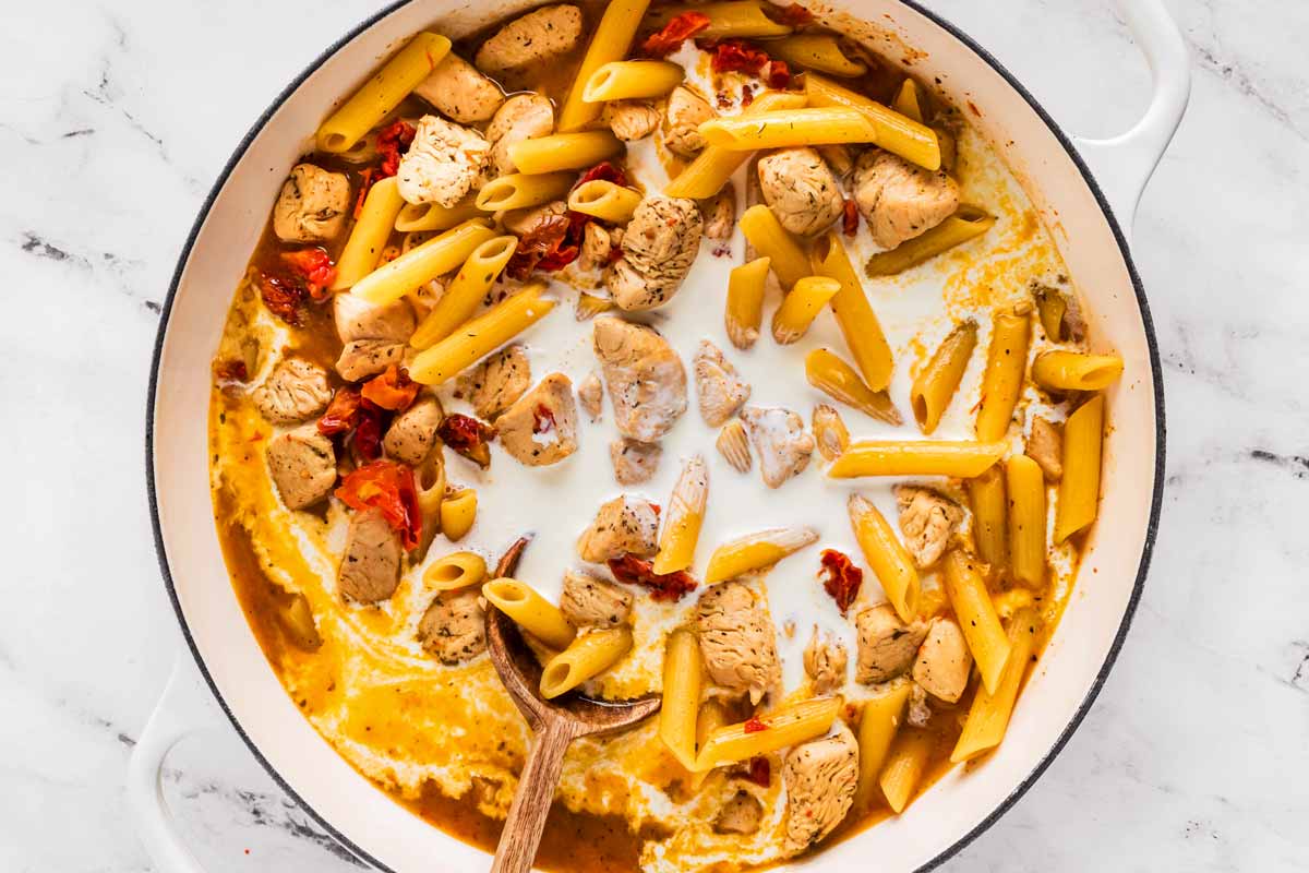 overhead view of uncooked marry me chicken pasta in pot with cream