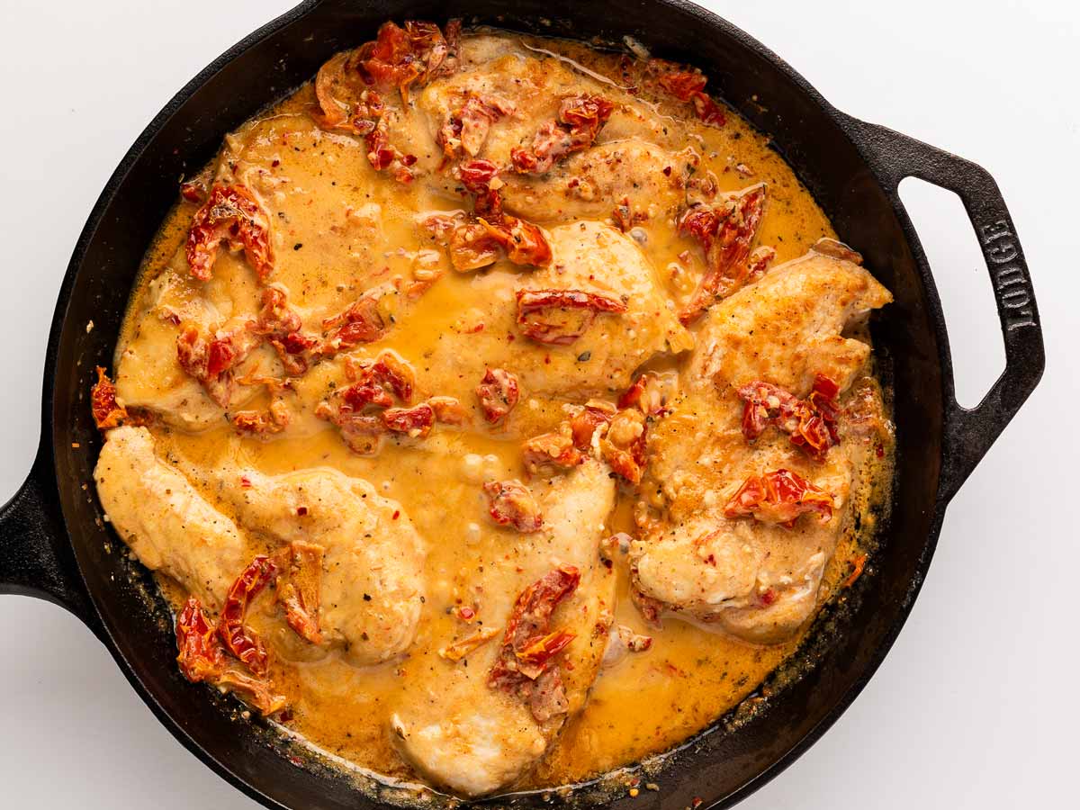 overhead view of seared chicken cutlets added to skillet with creamy sauce