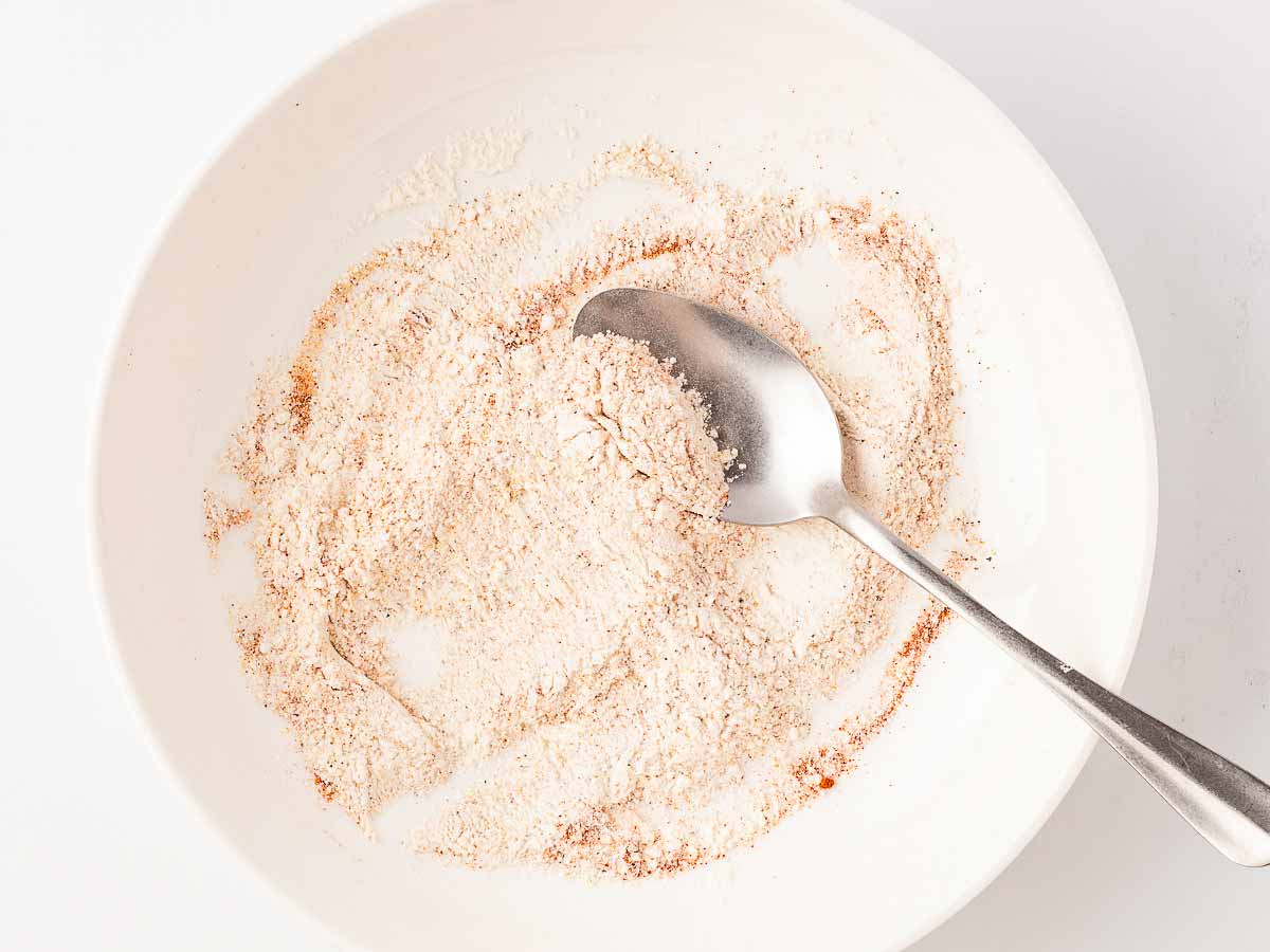 overhead view of seasoned flour in bowl with spoon