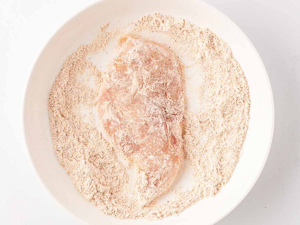 overhead view of chicken cutlets dredged in seasoned flour