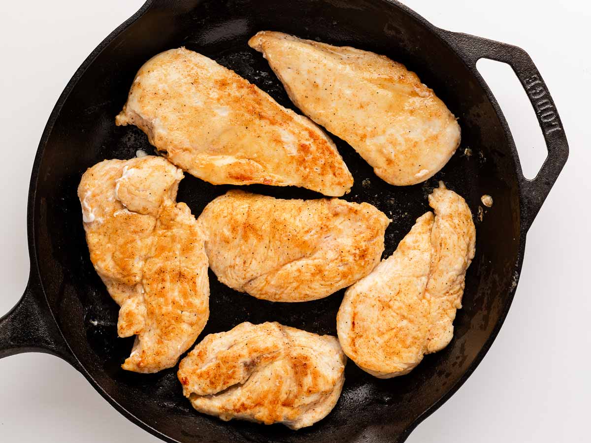 overhead view of golden brown seared chicken cutlets in skillet