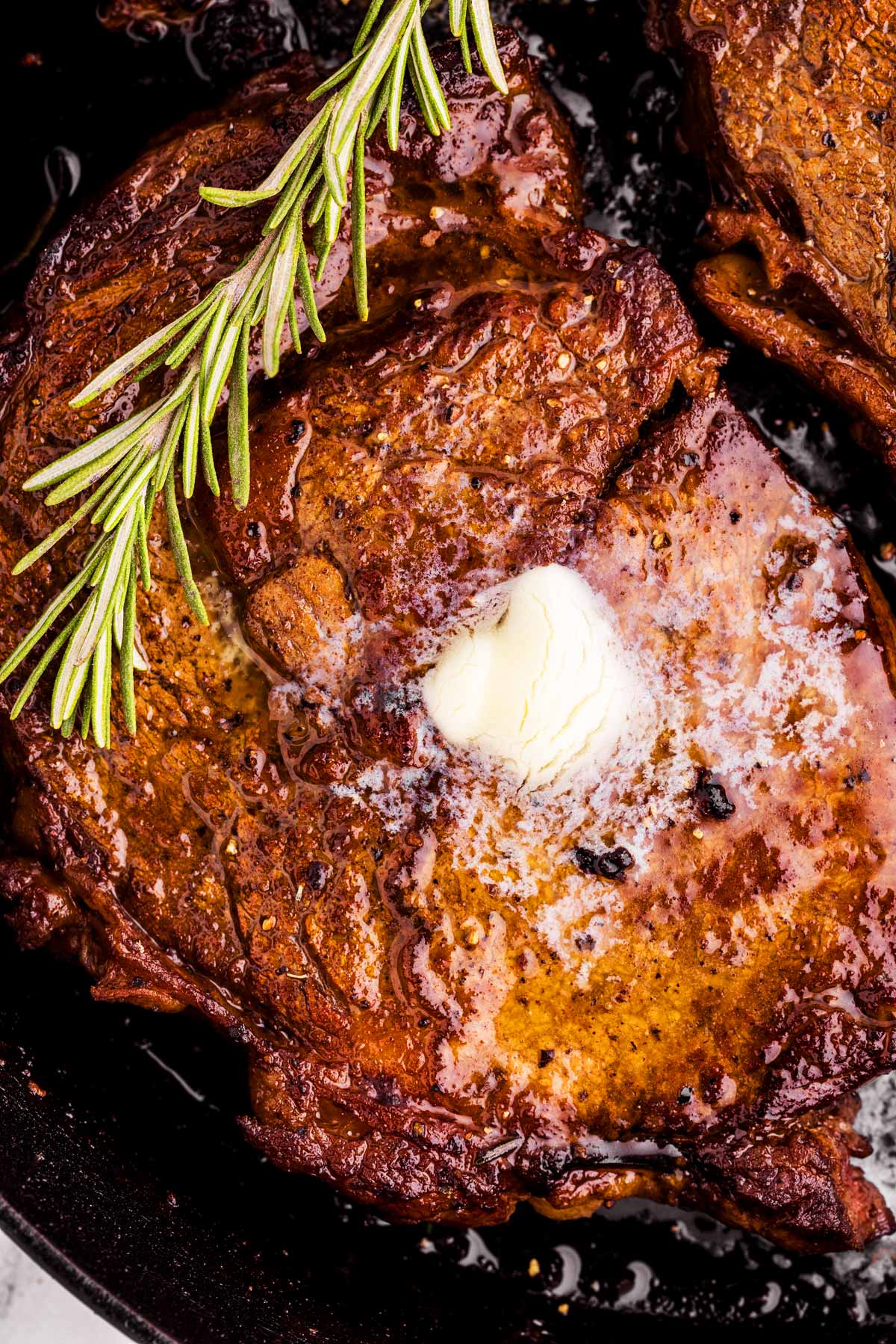 frontal close up view of pan seared steak topped with butter