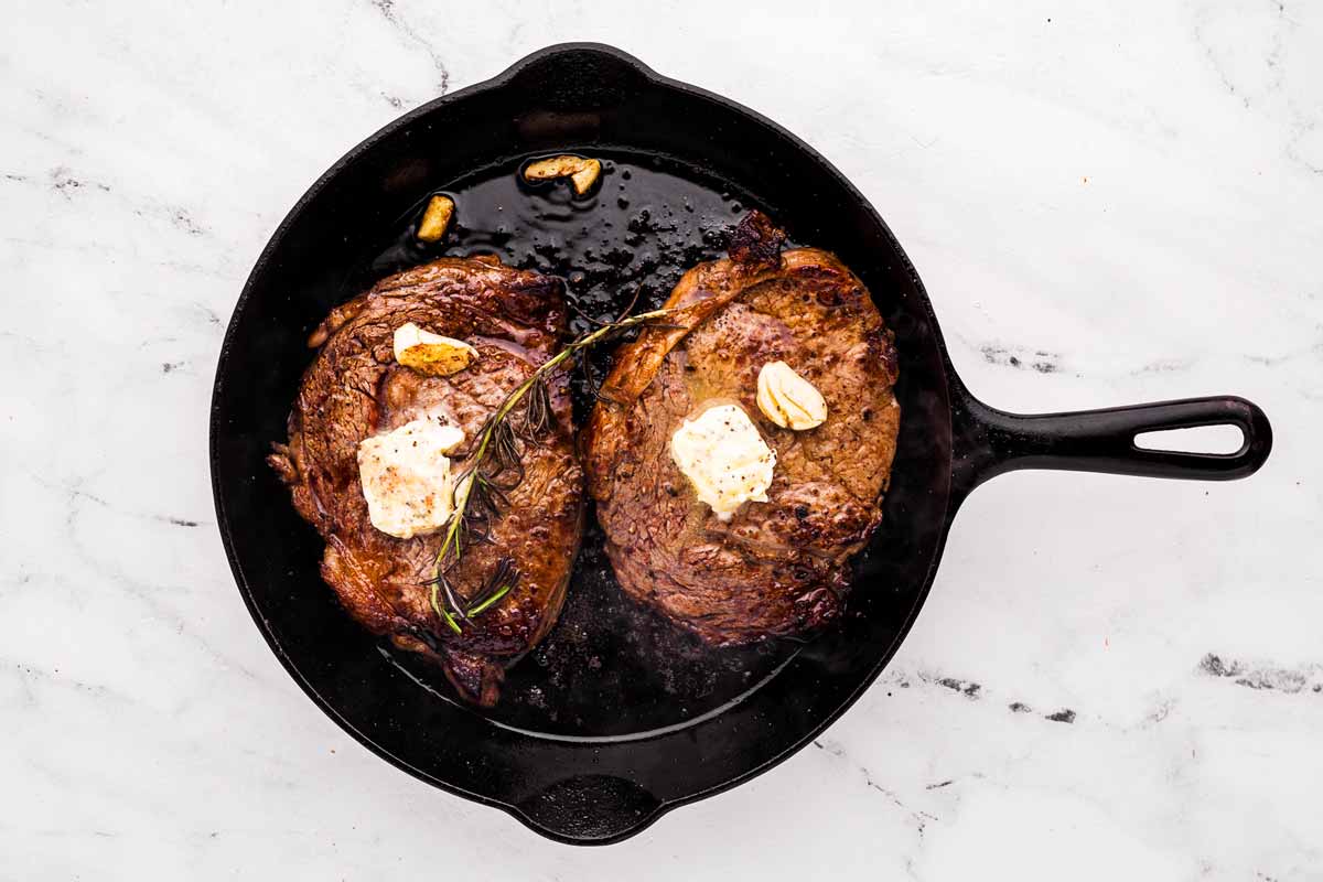 overhead view of seared steak basted with butter in skillet