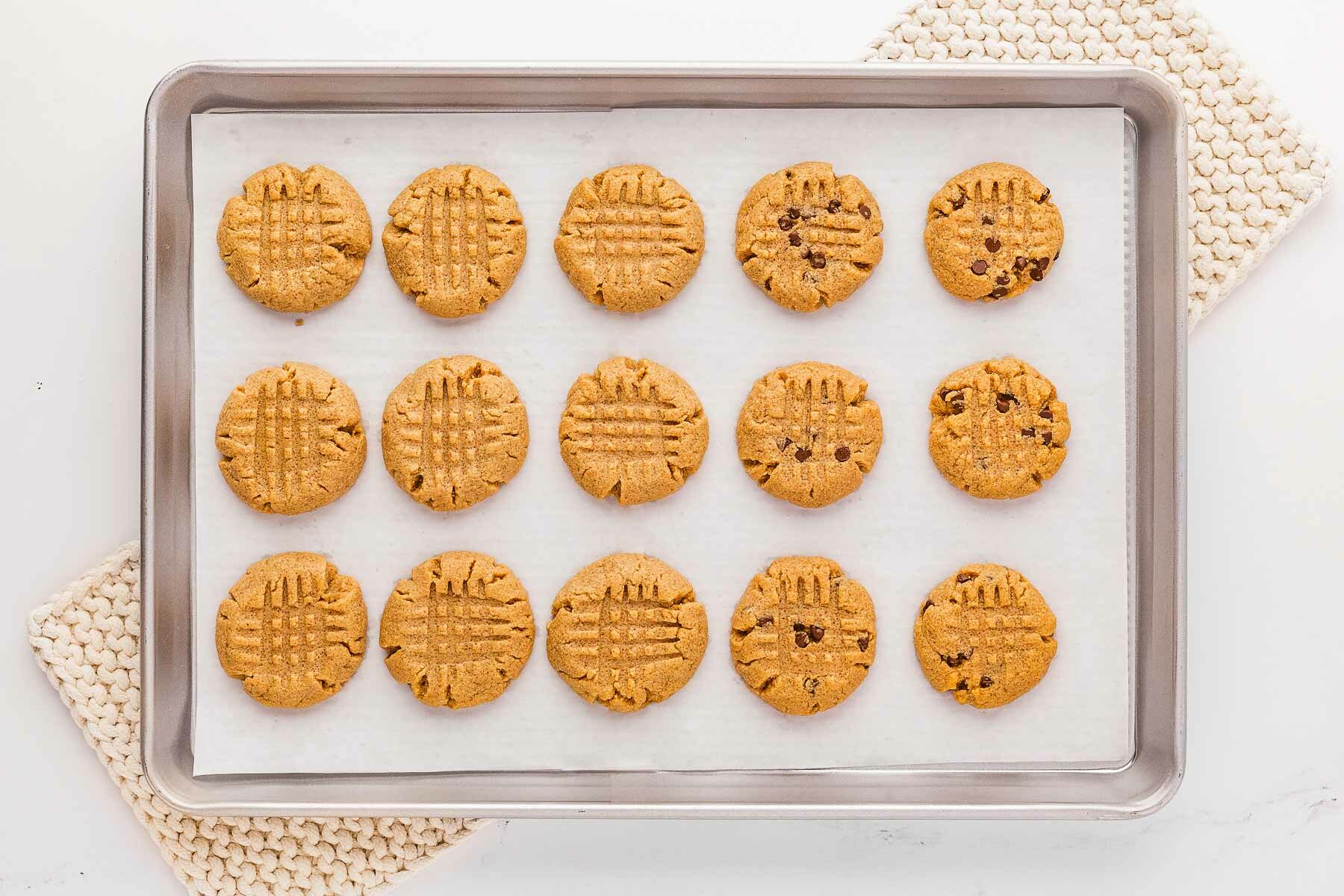 overhead view of baked peanut butter cookies on lined baking sheet