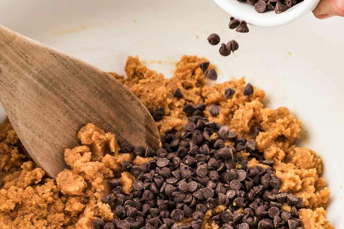 frontal view of chocolate chips being added to bowl of cookie dough