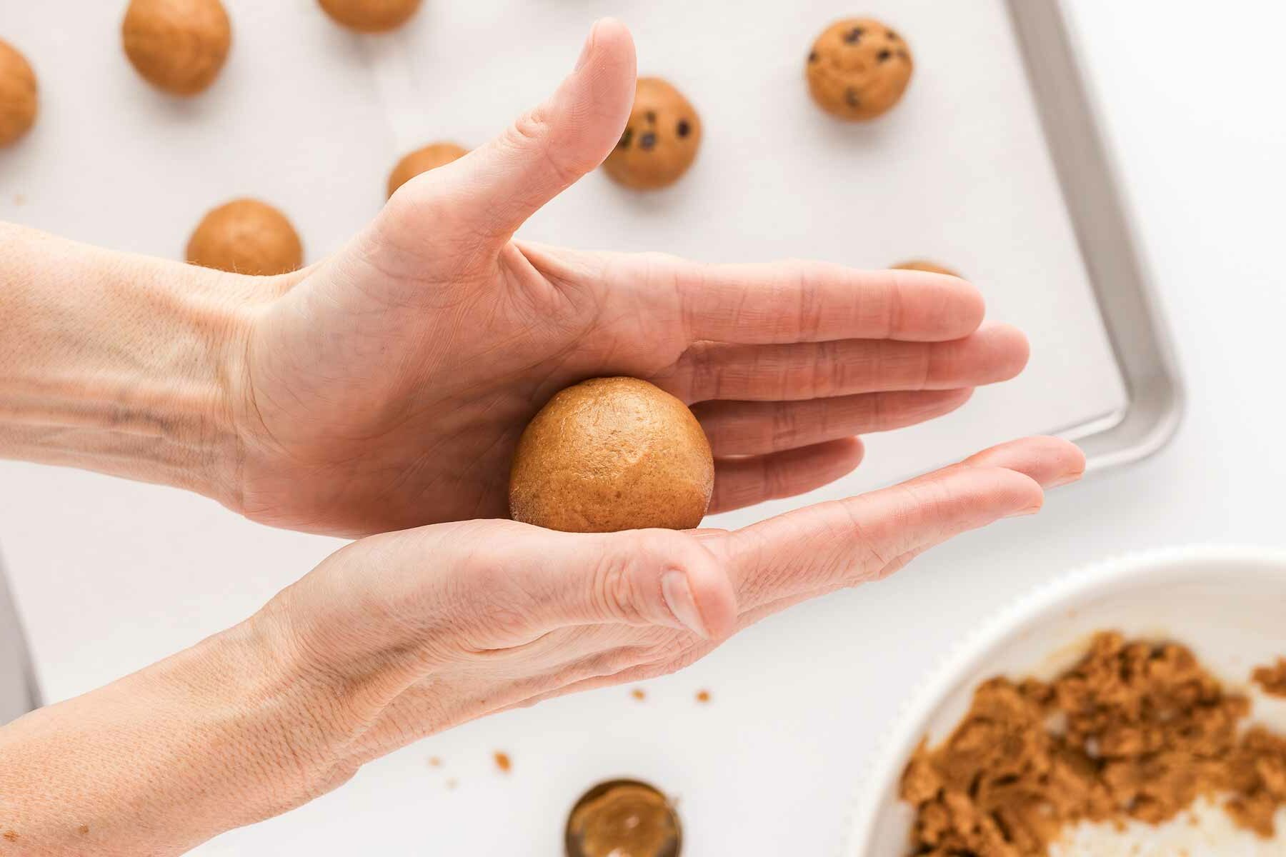 female hands rolling peanut butter cookie dough into ball