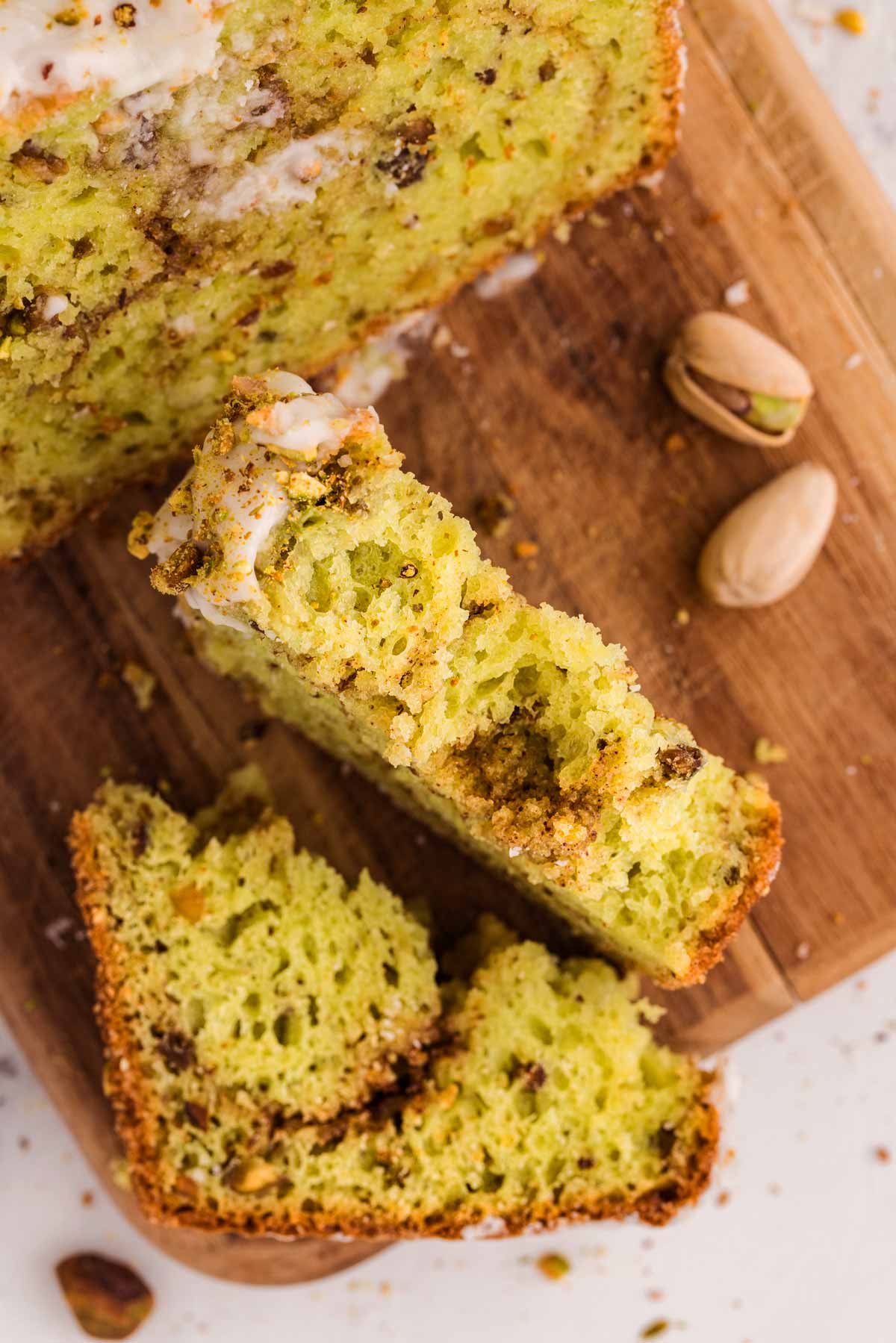 overhead view of halved slice of pistachio bread on wooden board